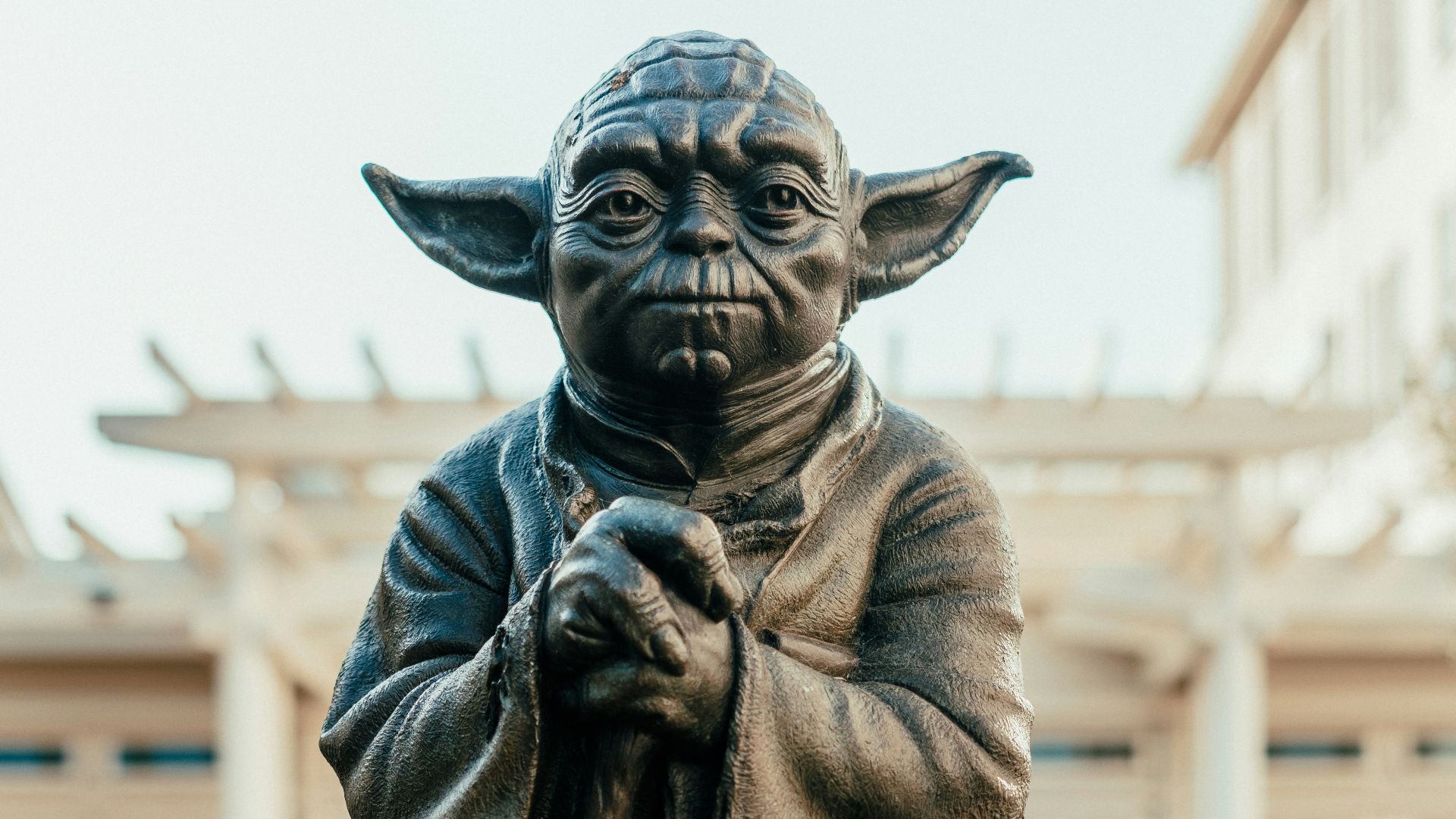 a statue of yoda holding a staff in front of a building