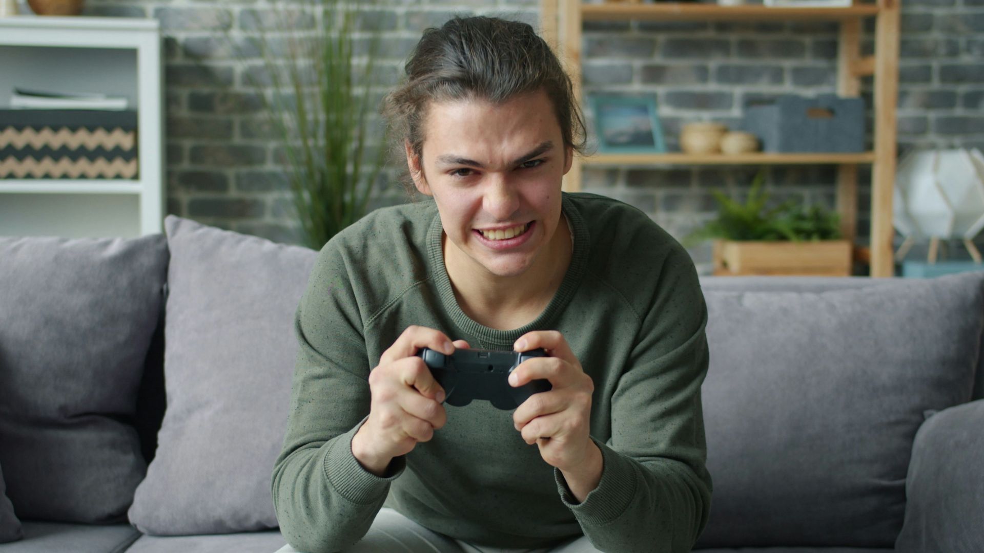 Young man intensely playing video games on couch