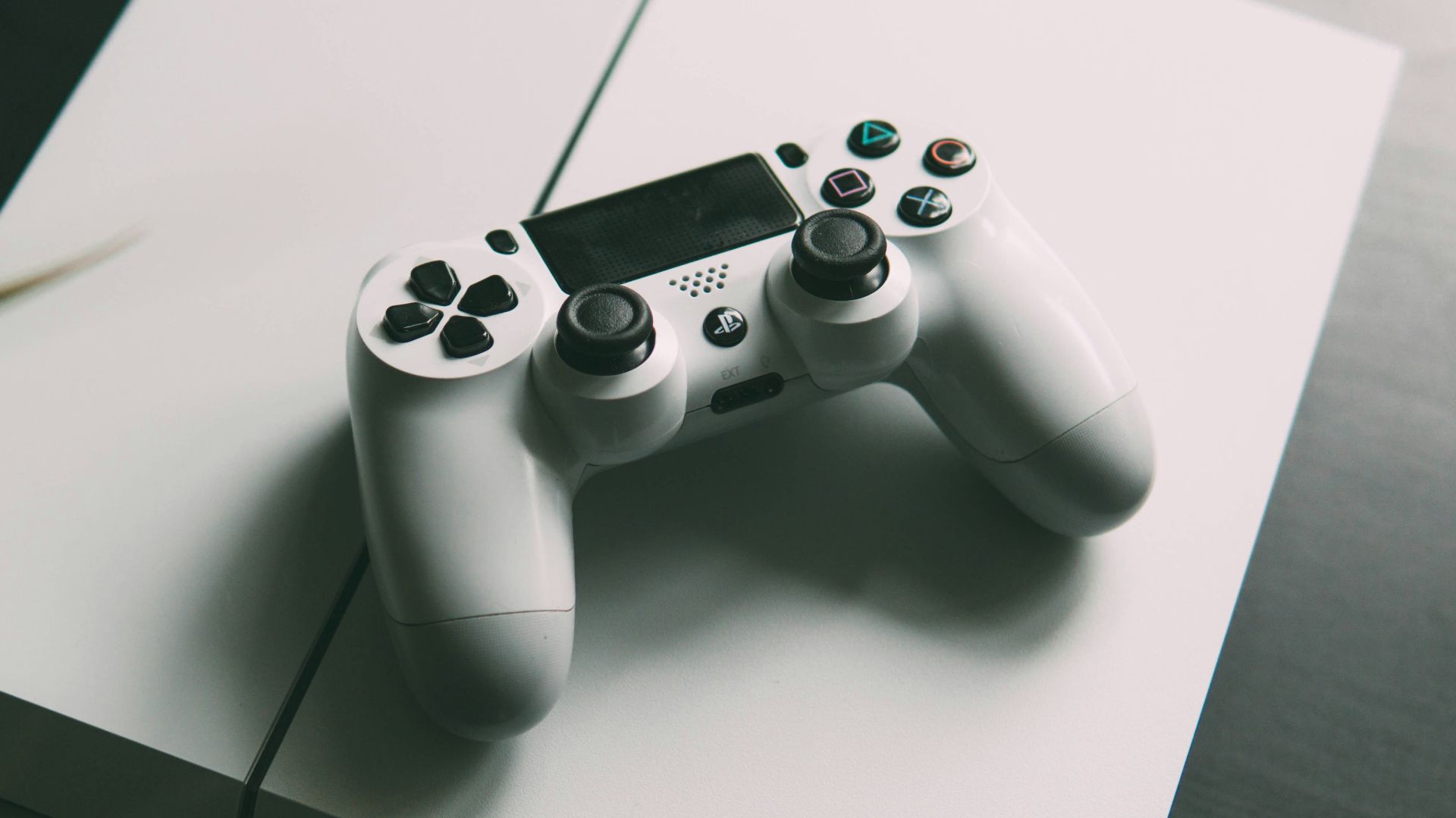 selective focus photography of white Sony PS4 console with wireless controller