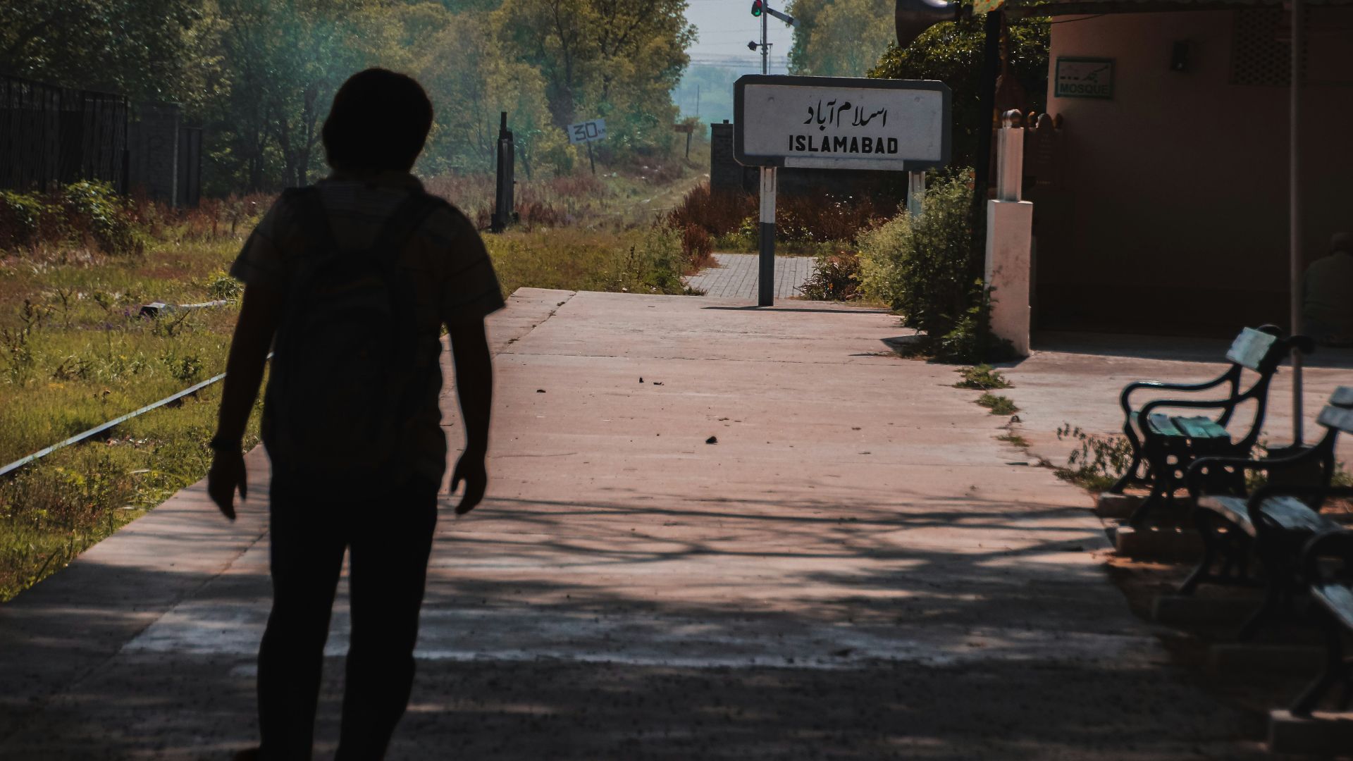 a man walking down a sidewalk next to a train station