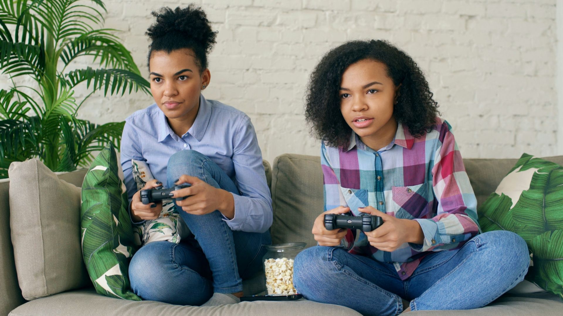 Two women playing video games on a couch.