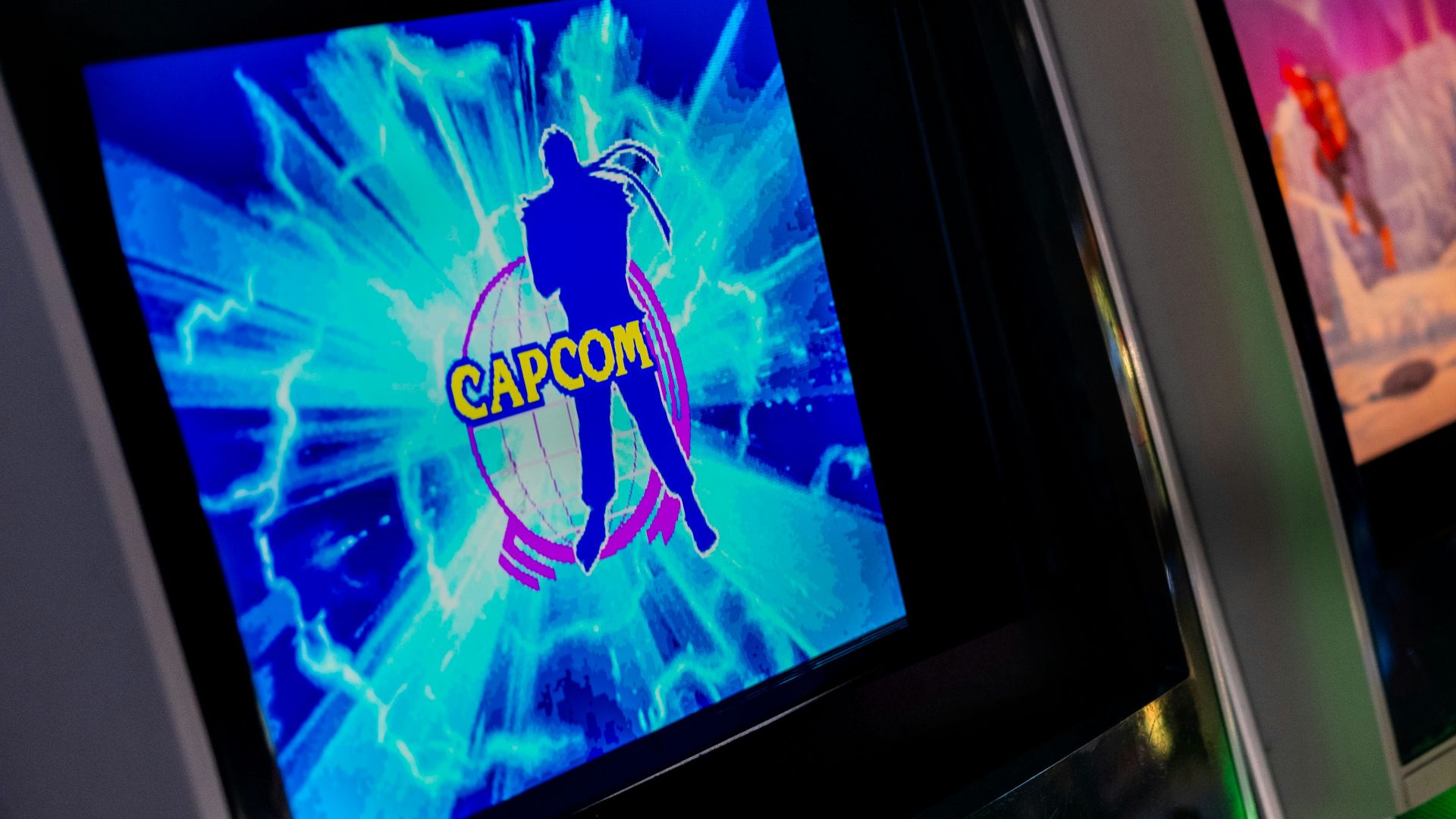 Row of glowing arcade game machines in darkness