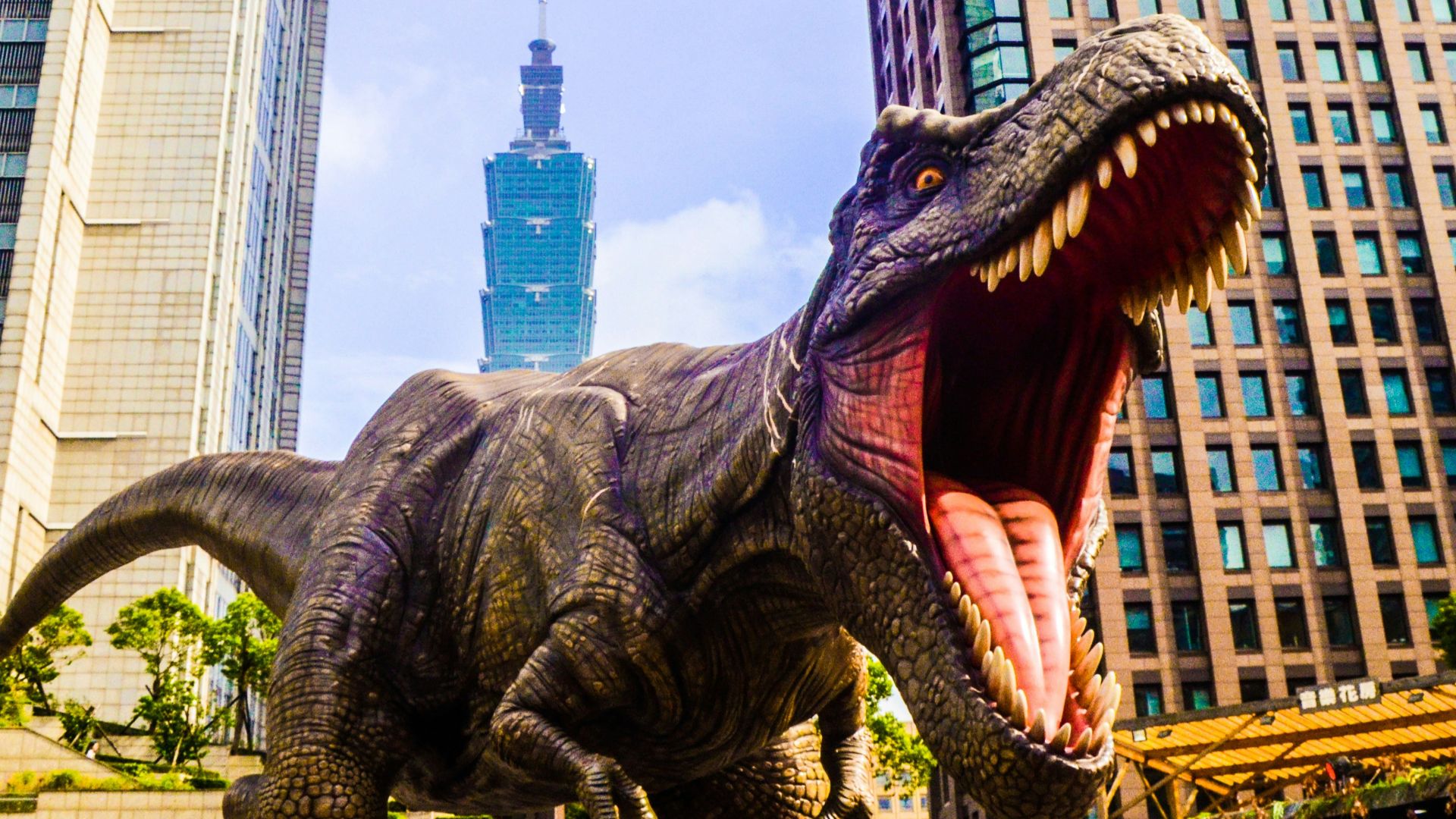 dinosaur with open mouth beside buildings still selective focus photography of