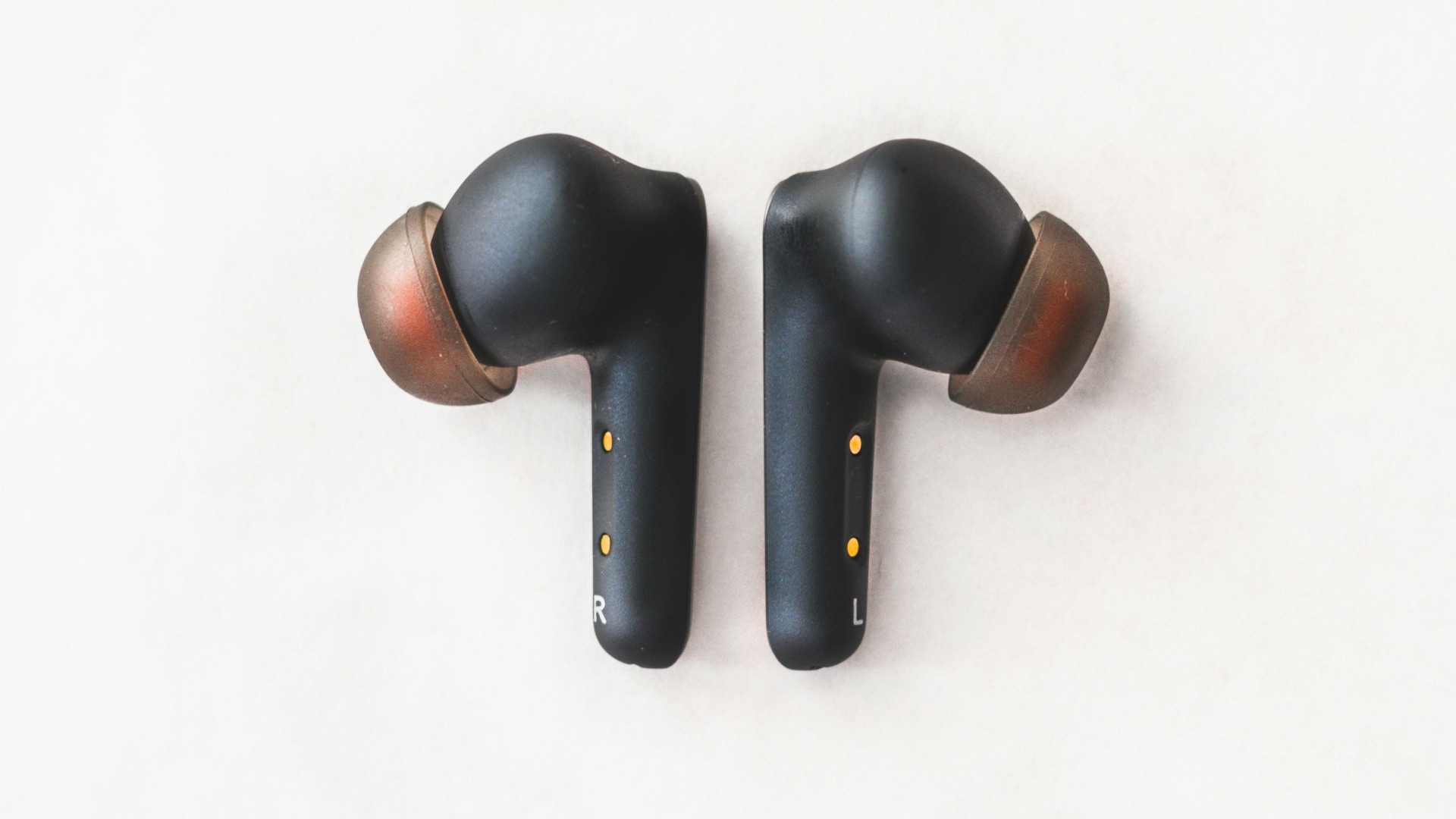 a pair of black ear buds sitting on top of a white surface