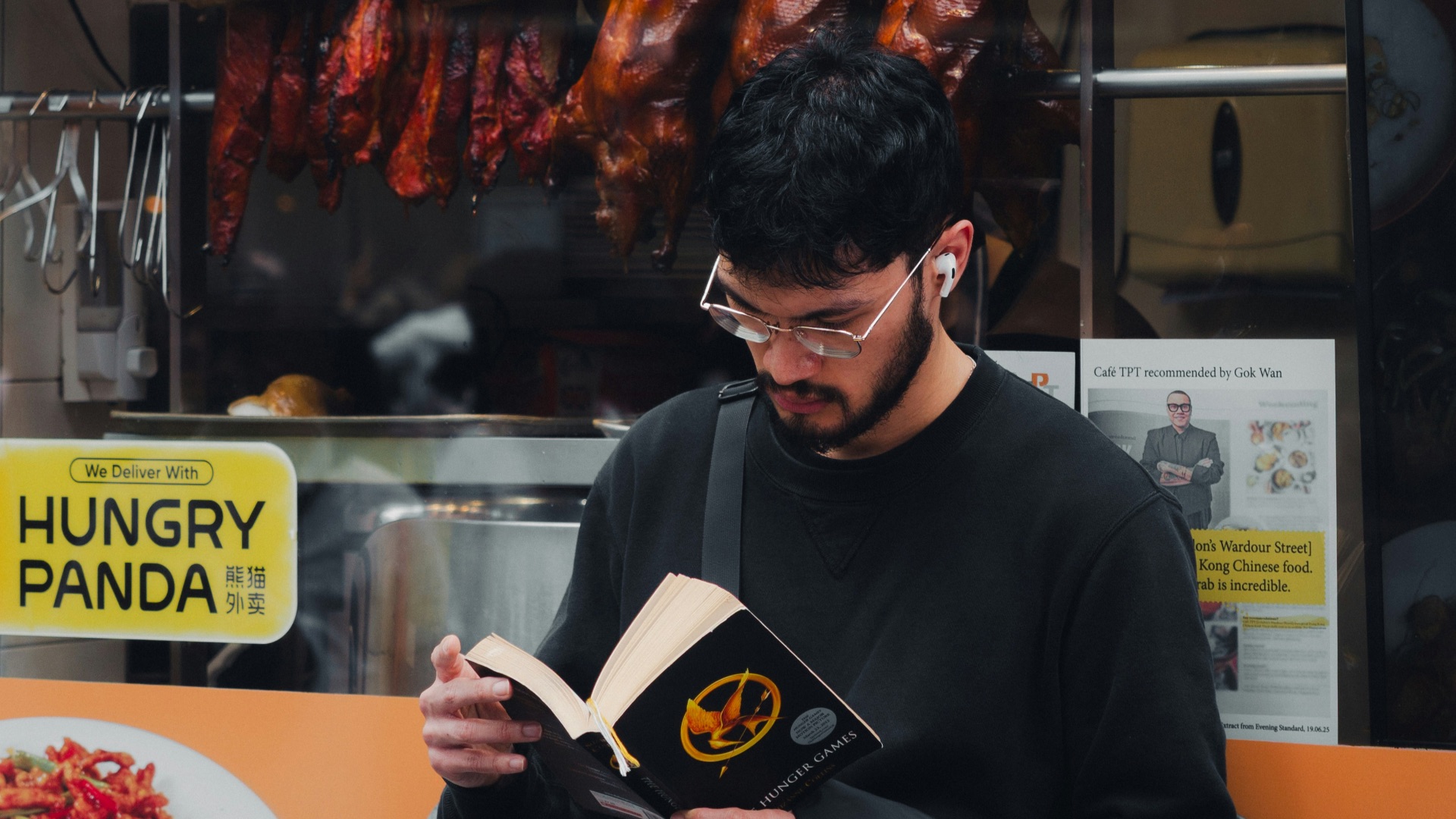 Man reading a book outside a restaurant