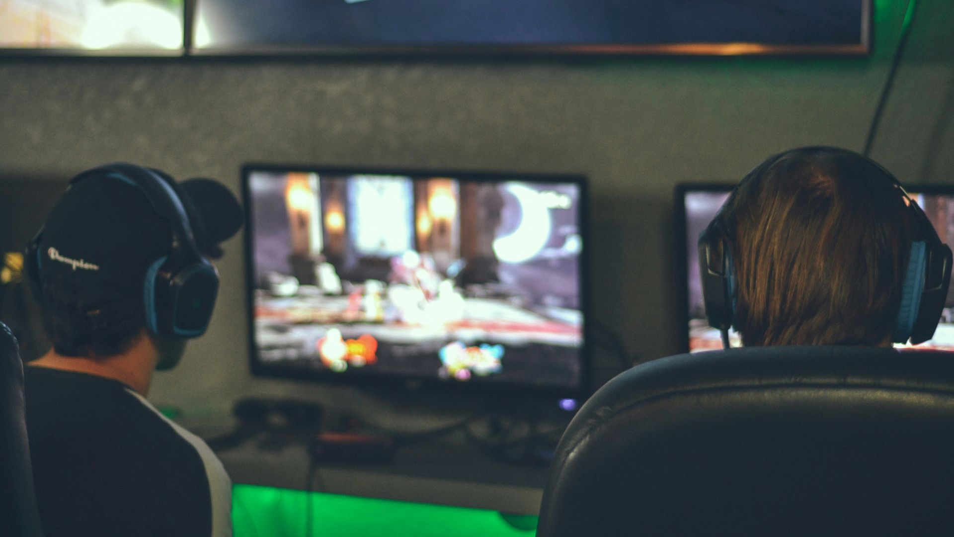 selective focus photography of two persons playing game in front of monitors