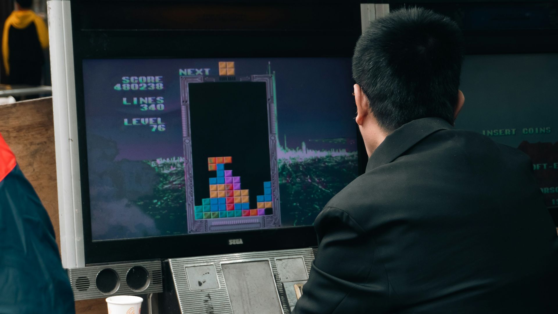 A man plays tetris on a vintage arcade game.