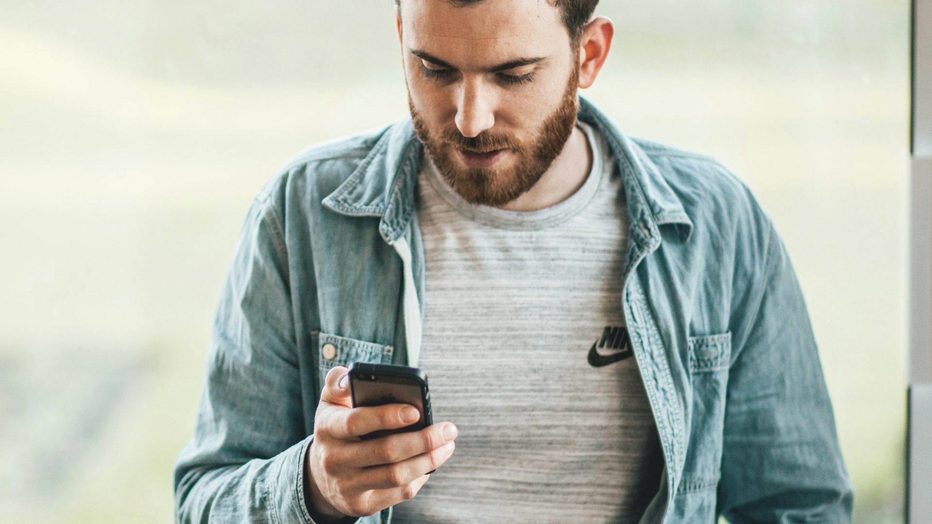 man holding a smartphone near the window
