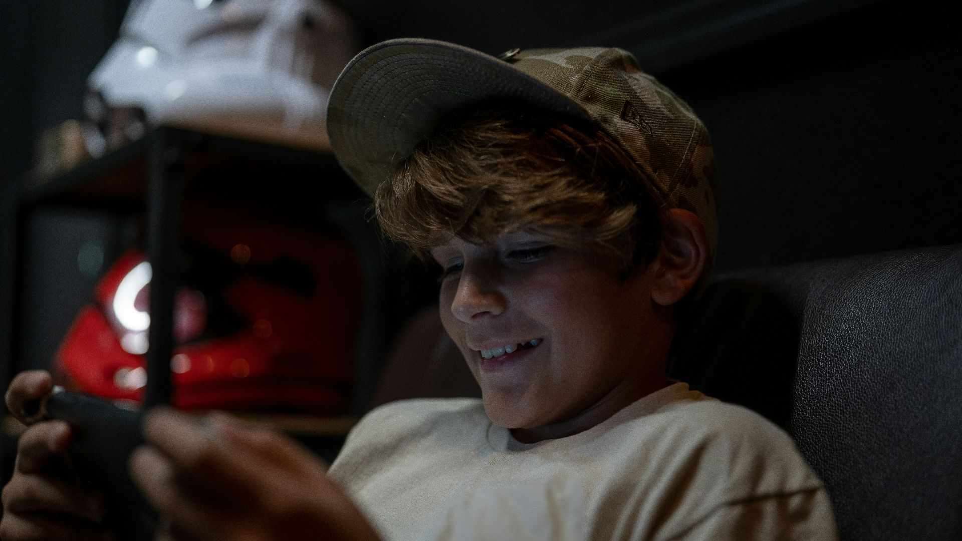 a young boy sitting in a chair looking at a cell phone