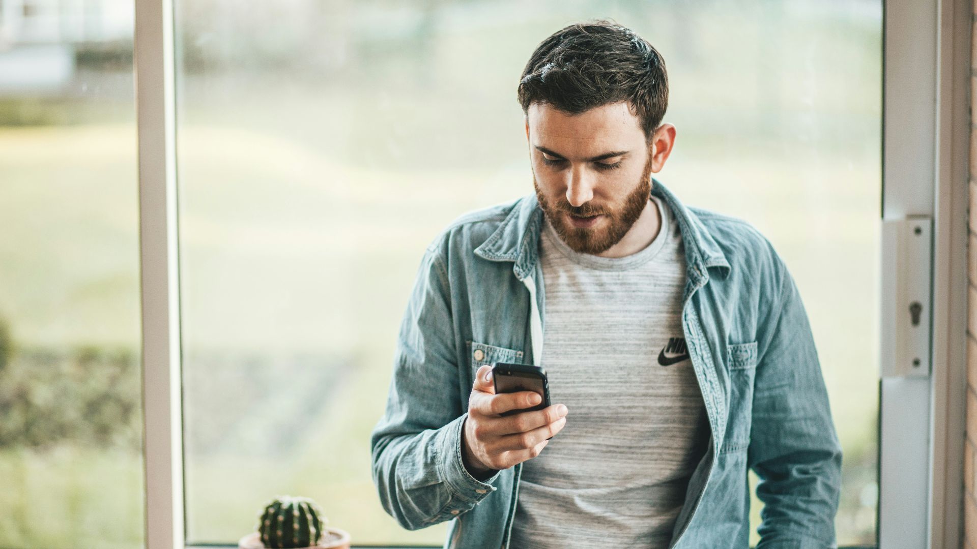 man holding a smartphone near the window