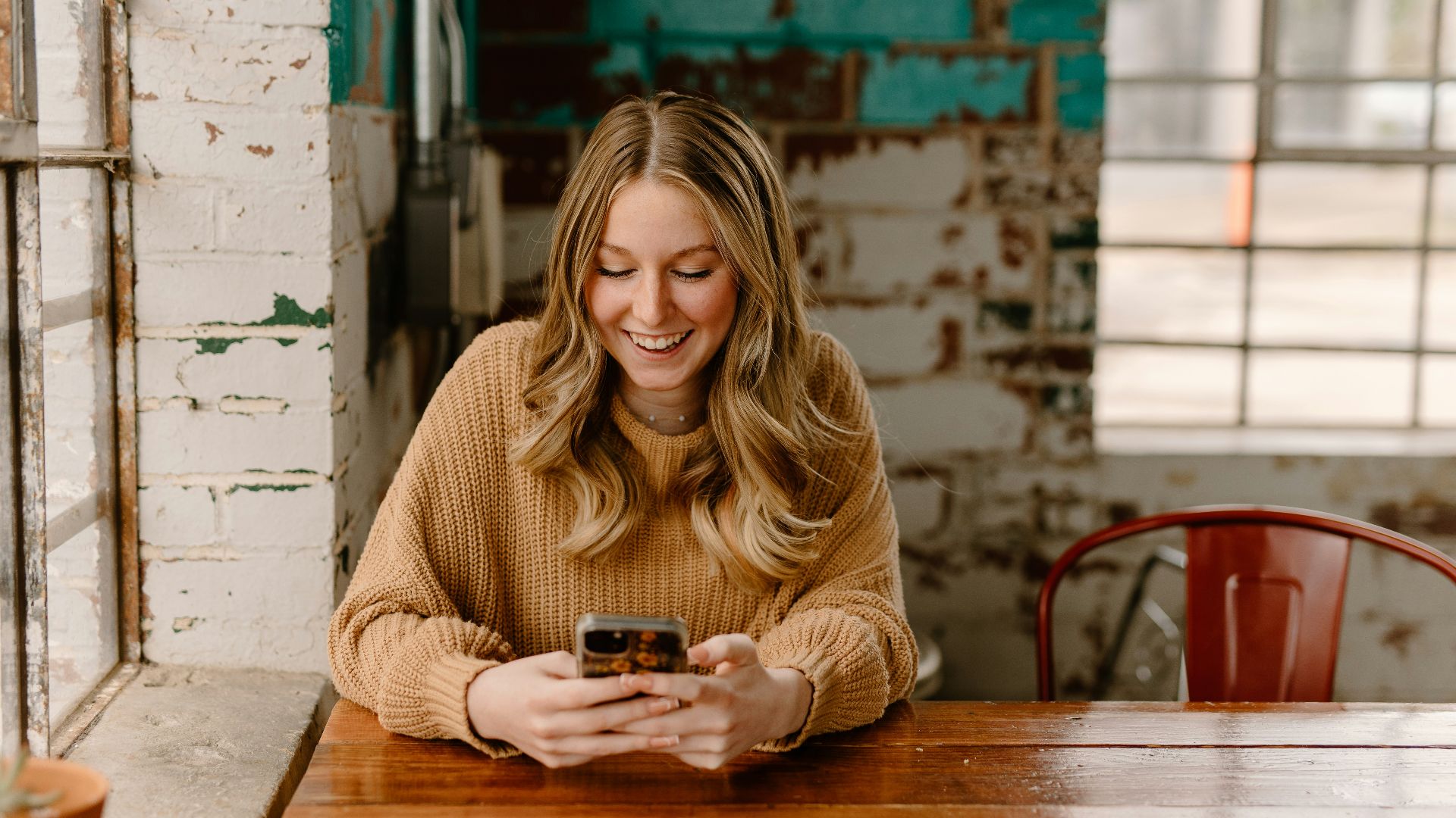 a woman sitting at a table looking at her cell phone