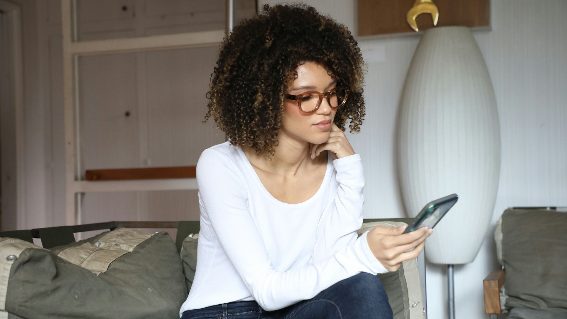 woman in white long sleeve shirt and blue denim jeans sitting on bed