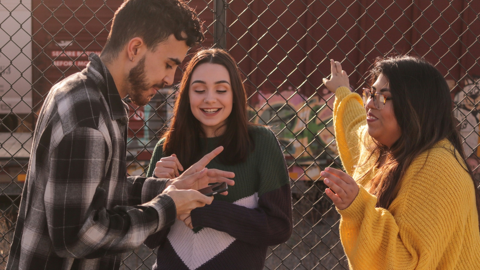man and two women standing near linked-chain fence
