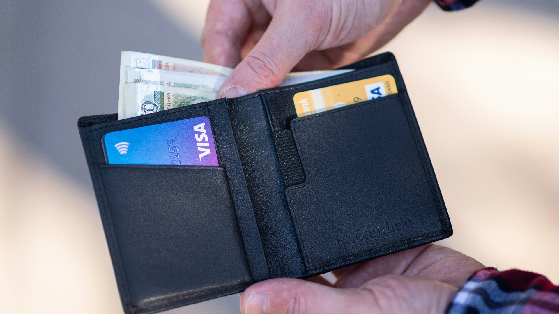 black leather bifold wallet on persons hand