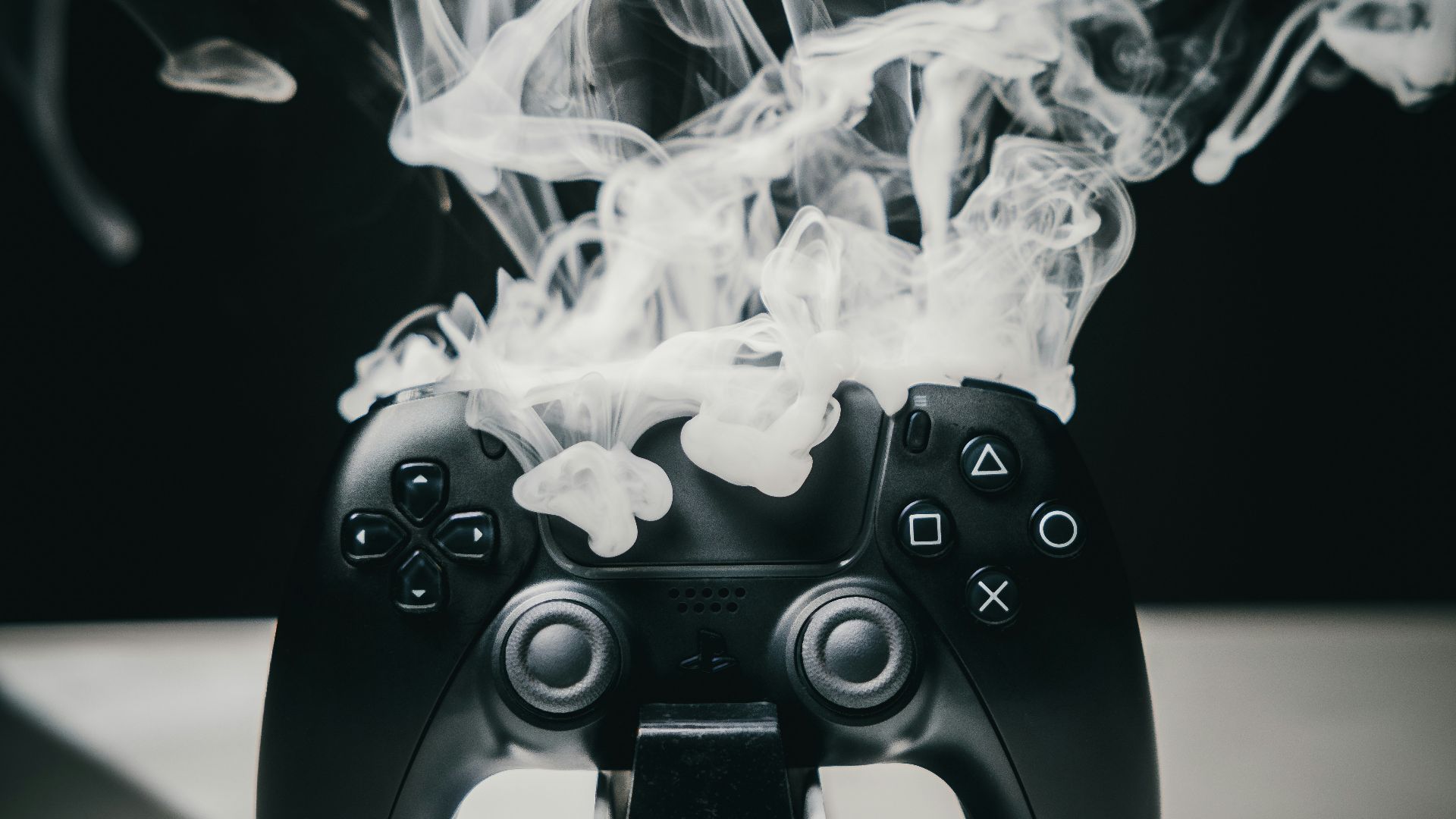 A black video game controller emitting smoke