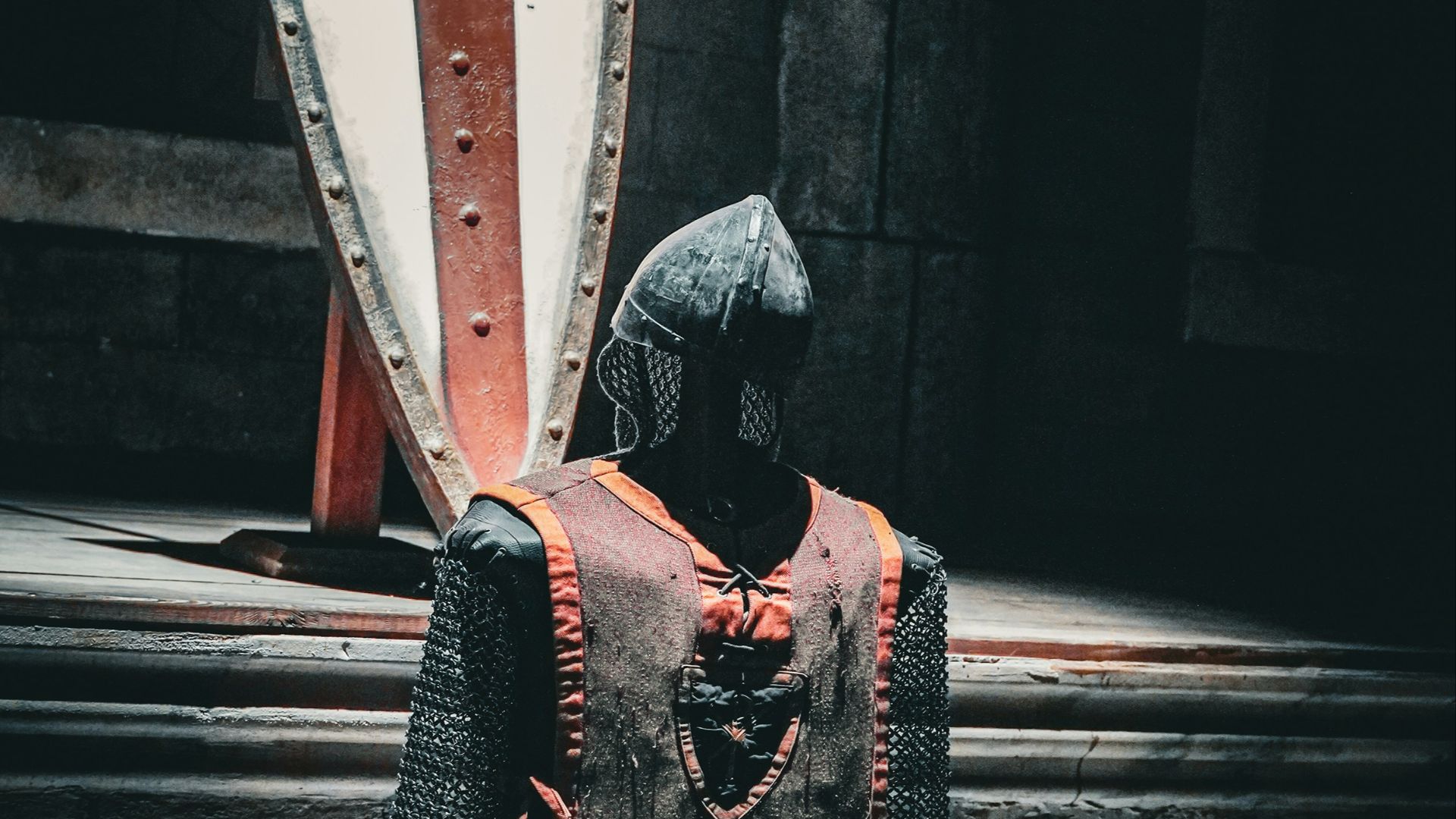 A knight is standing in front of a large shield