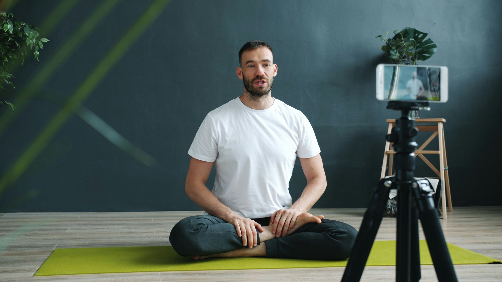 Man meditating in front of a phone camera