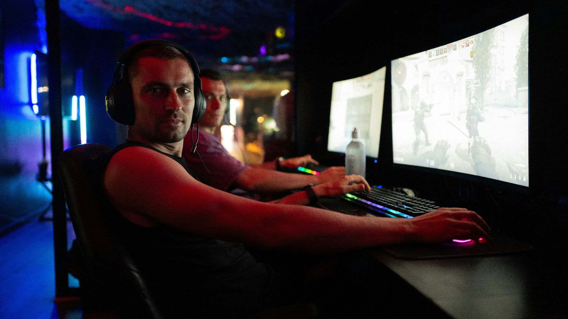 Men playing video games in a dimly lit room.