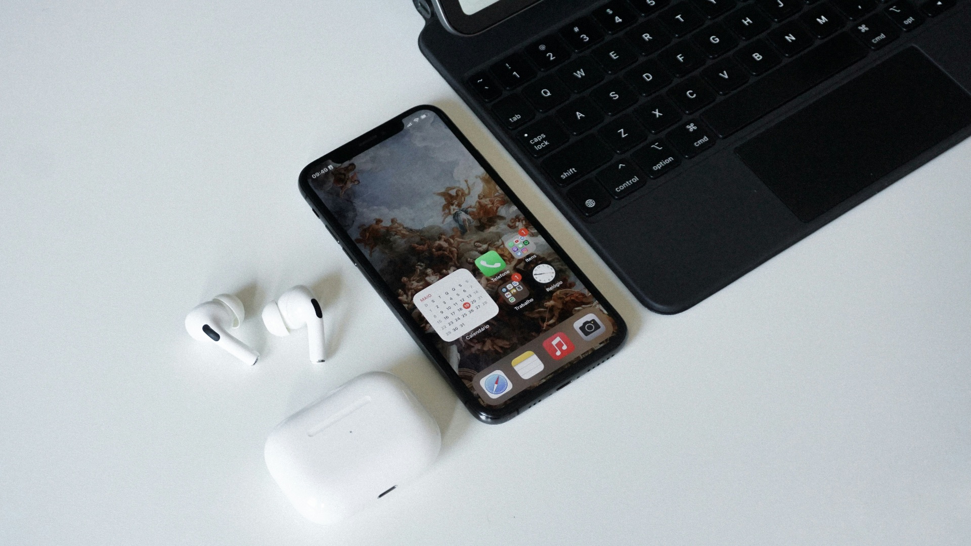 an iphone, ear buds, and laptop on a table