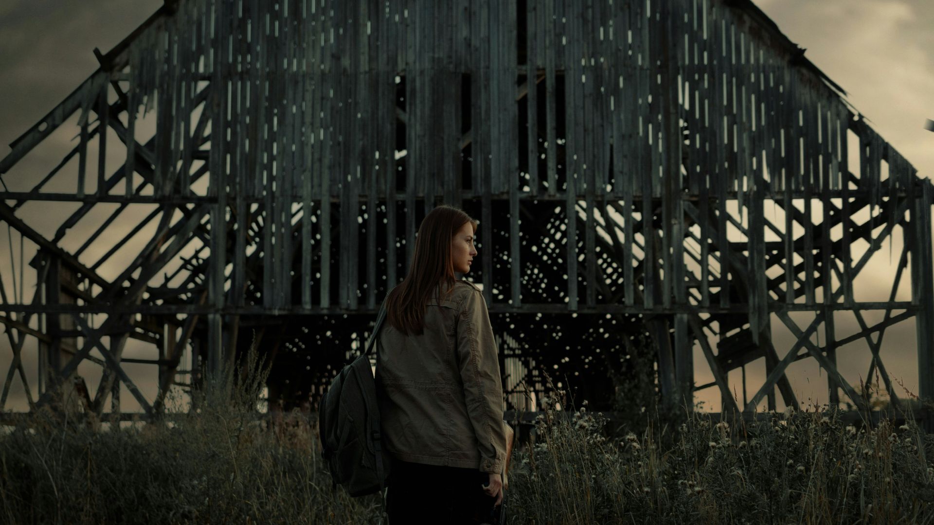man in white long sleeve shirt standing beside brown wooden barn