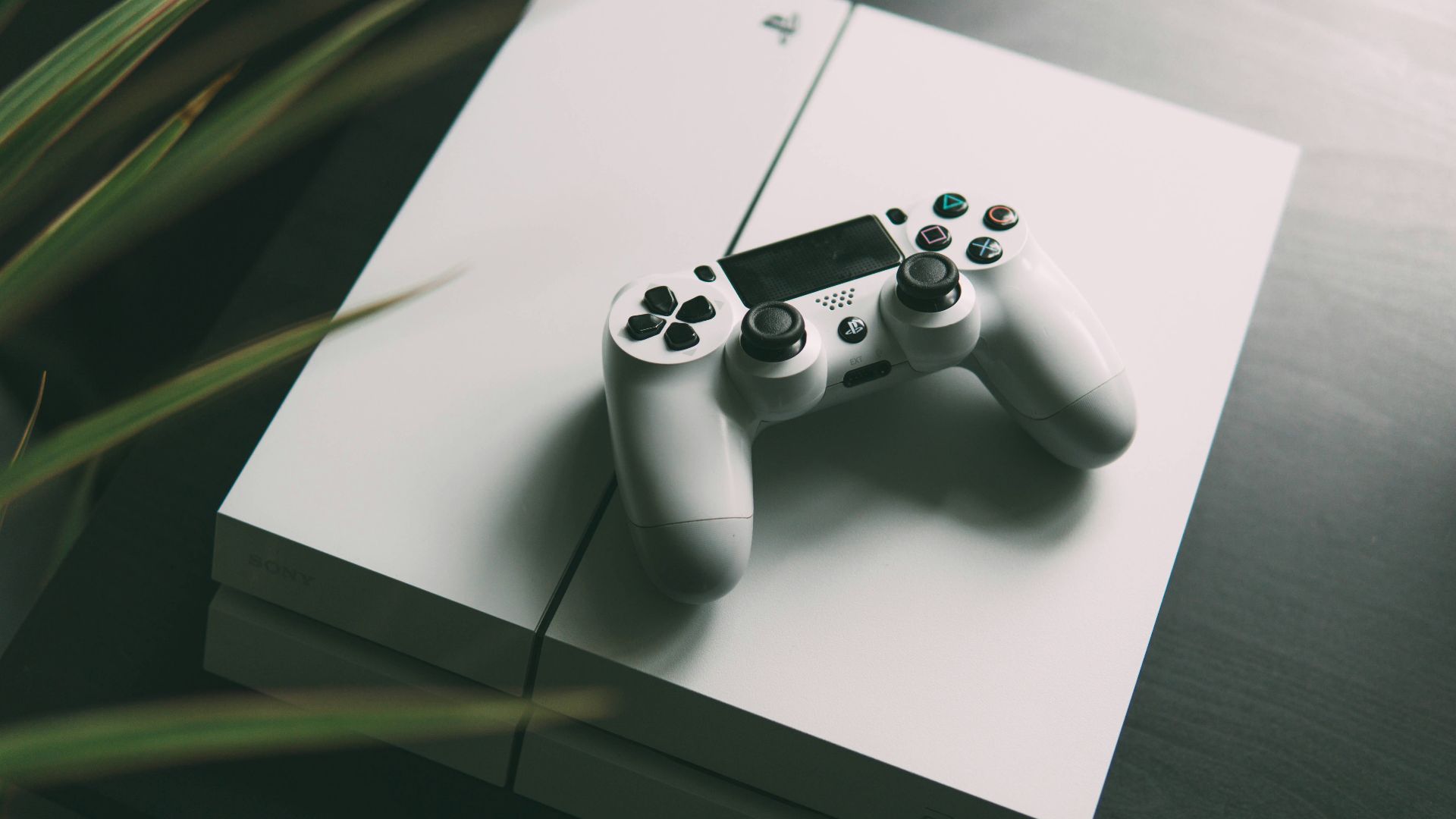 selective focus photography of white Sony PS4 console with wireless controller
