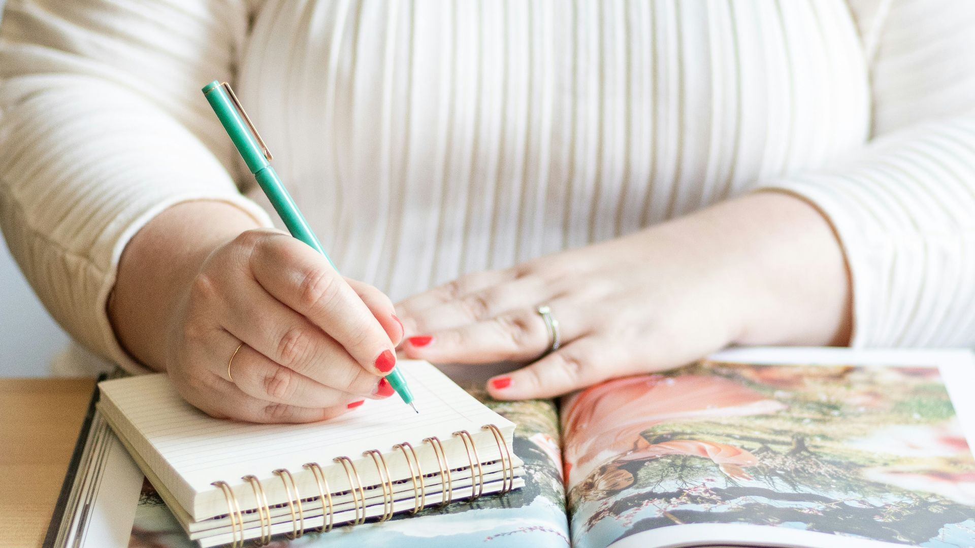 a woman is holding a pen and writing on a book