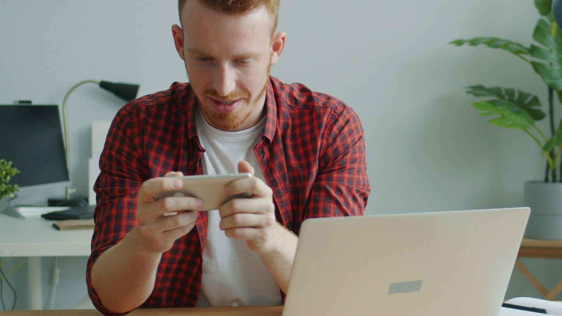 Man playing a video game on his phone at desk.