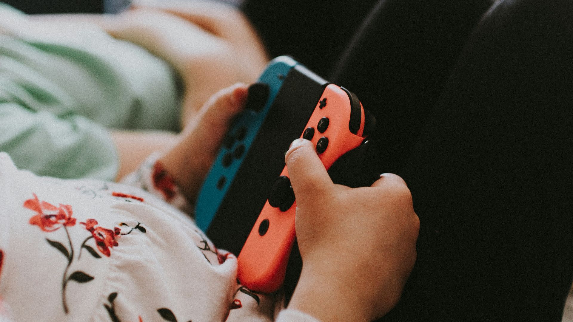 person holding blue and orange Joy Con controller