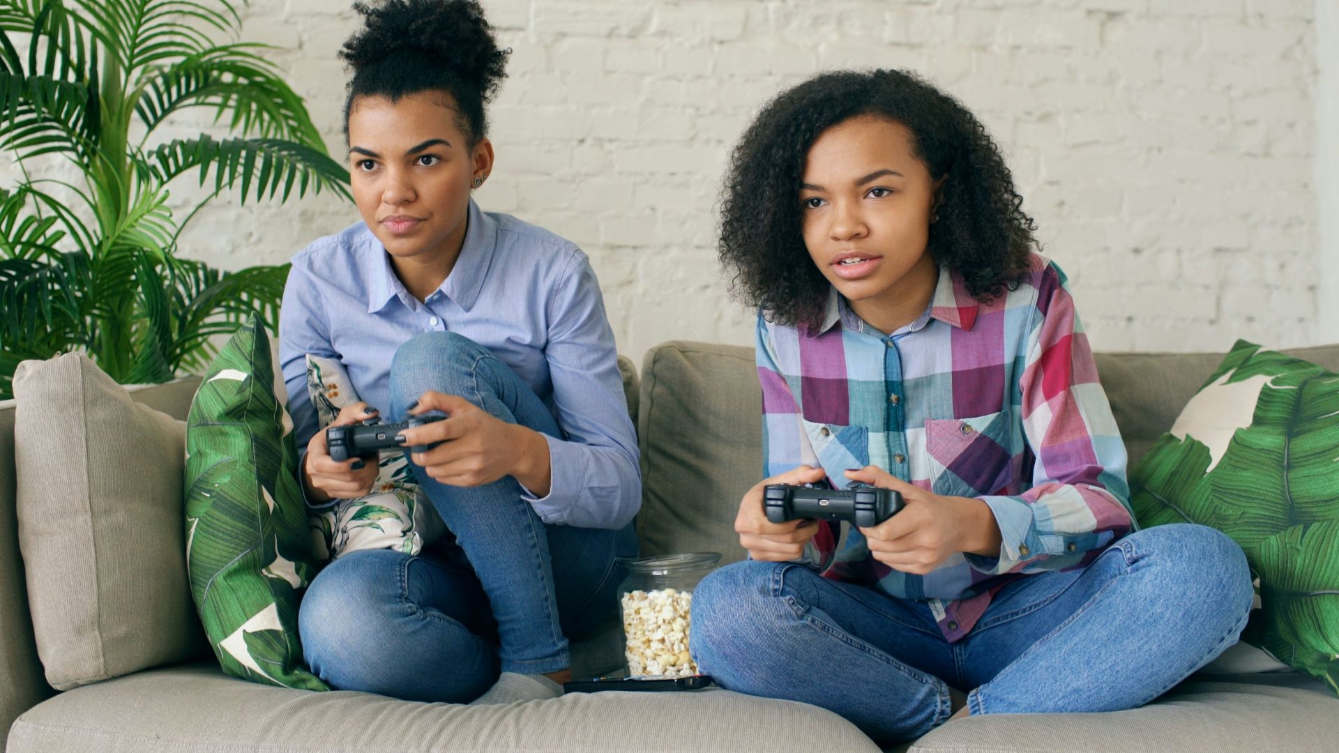 Two women playing video games on a couch.