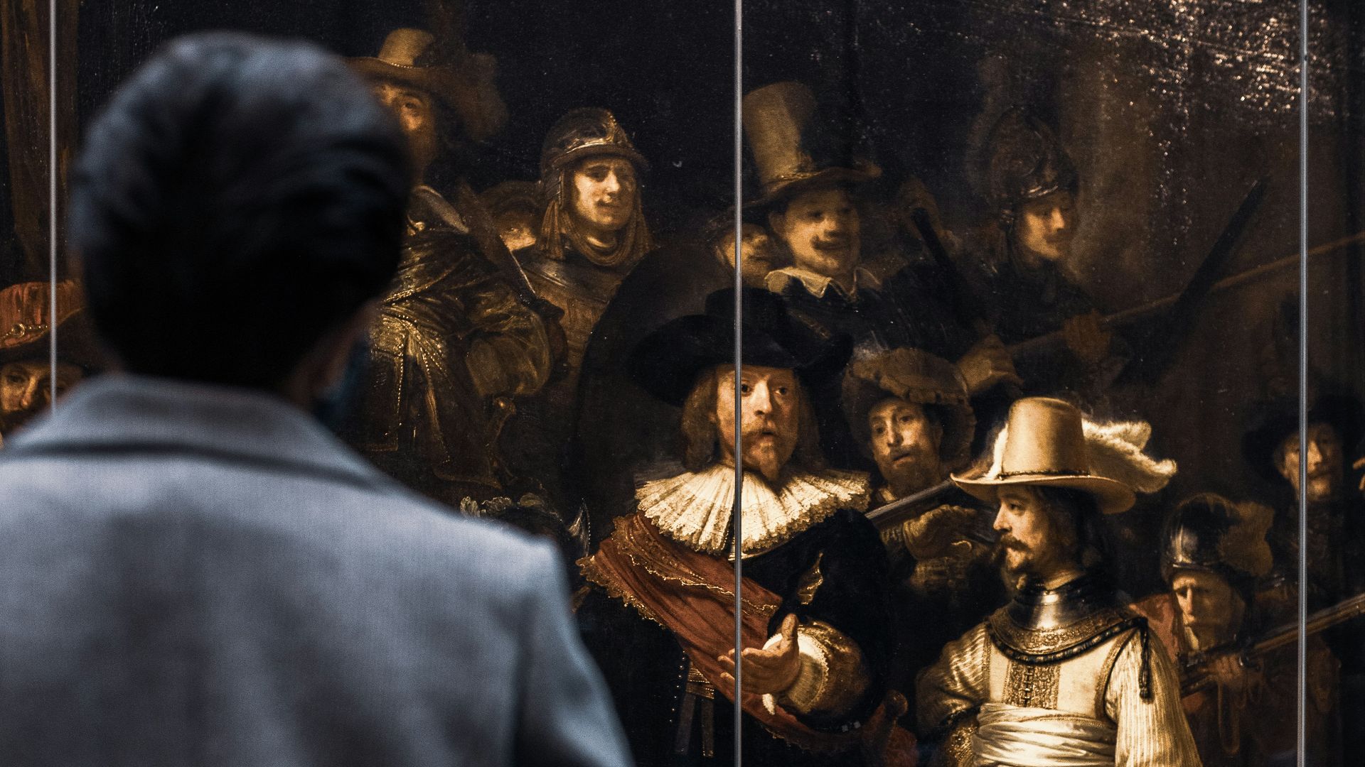 a man looking at a painting of a man in armor