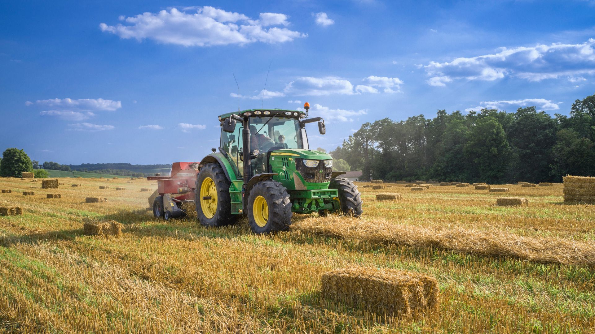 green tractor on brown grass field under blue sky during daytime