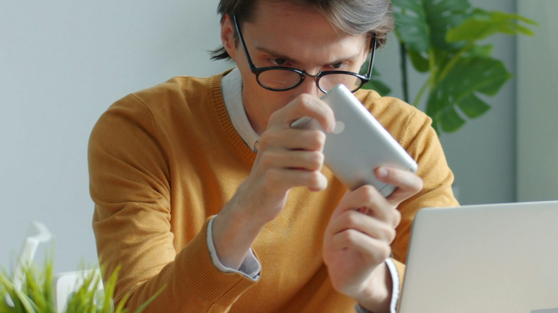 Man in yellow sweater drinking from mug at desk