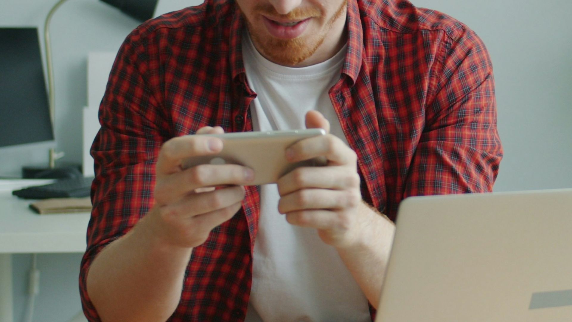 Man playing a video game on his phone at desk.