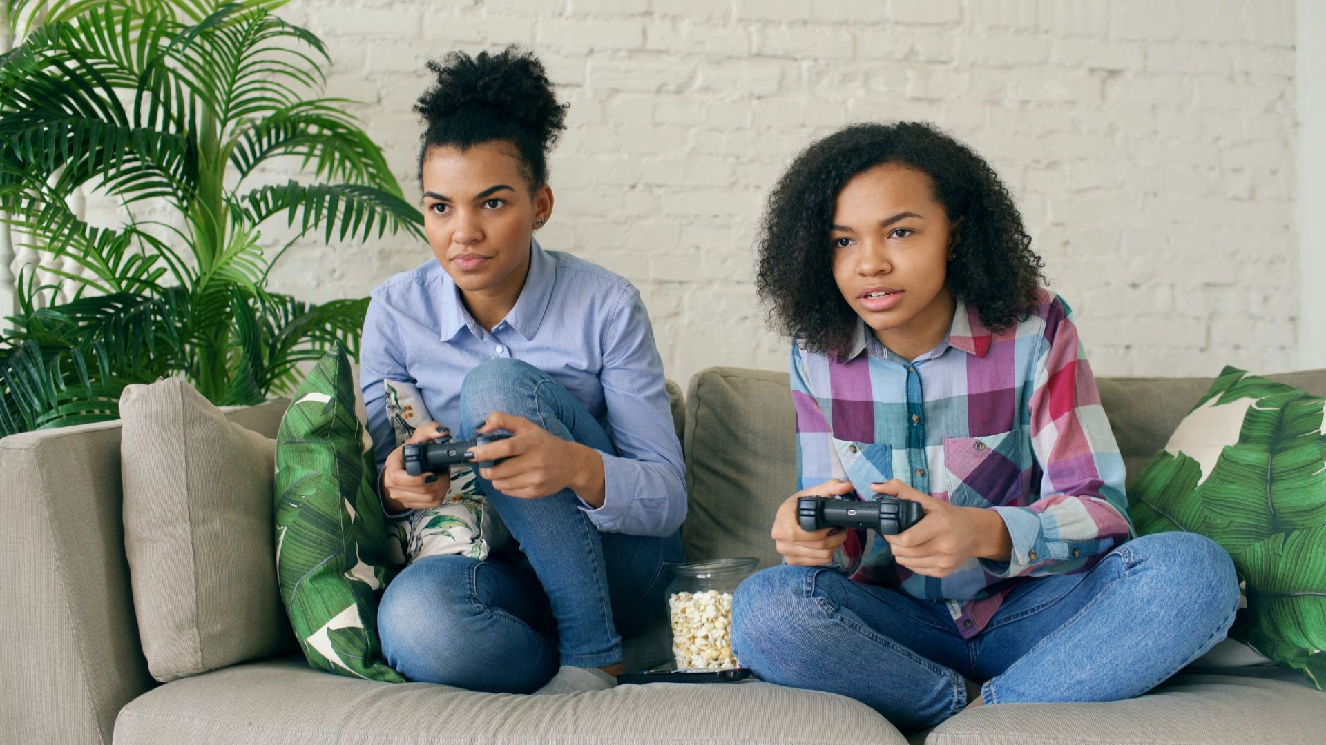 Two women playing video games on a couch.