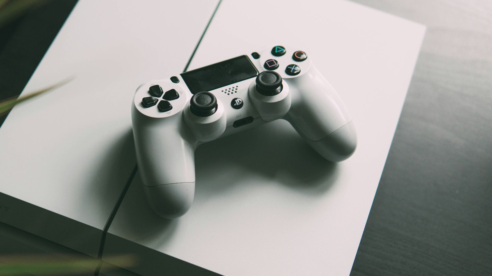 selective focus photography of white Sony PS4 console with wireless controller