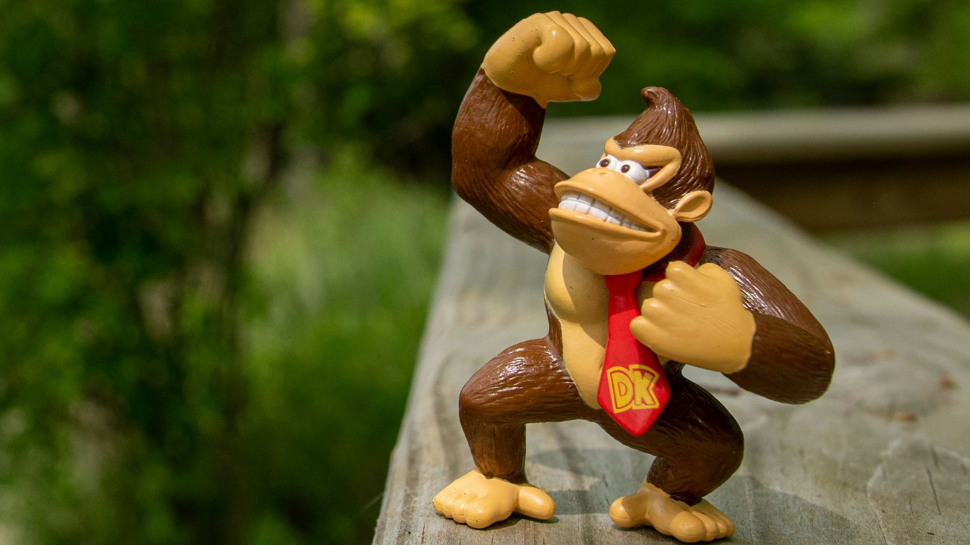 a monkey figurine is posed on a wooden deck