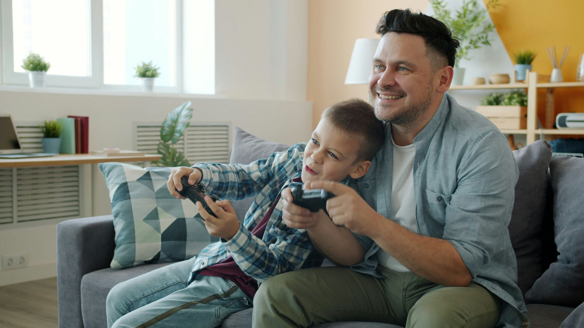 Father and son playing video games together on couch.