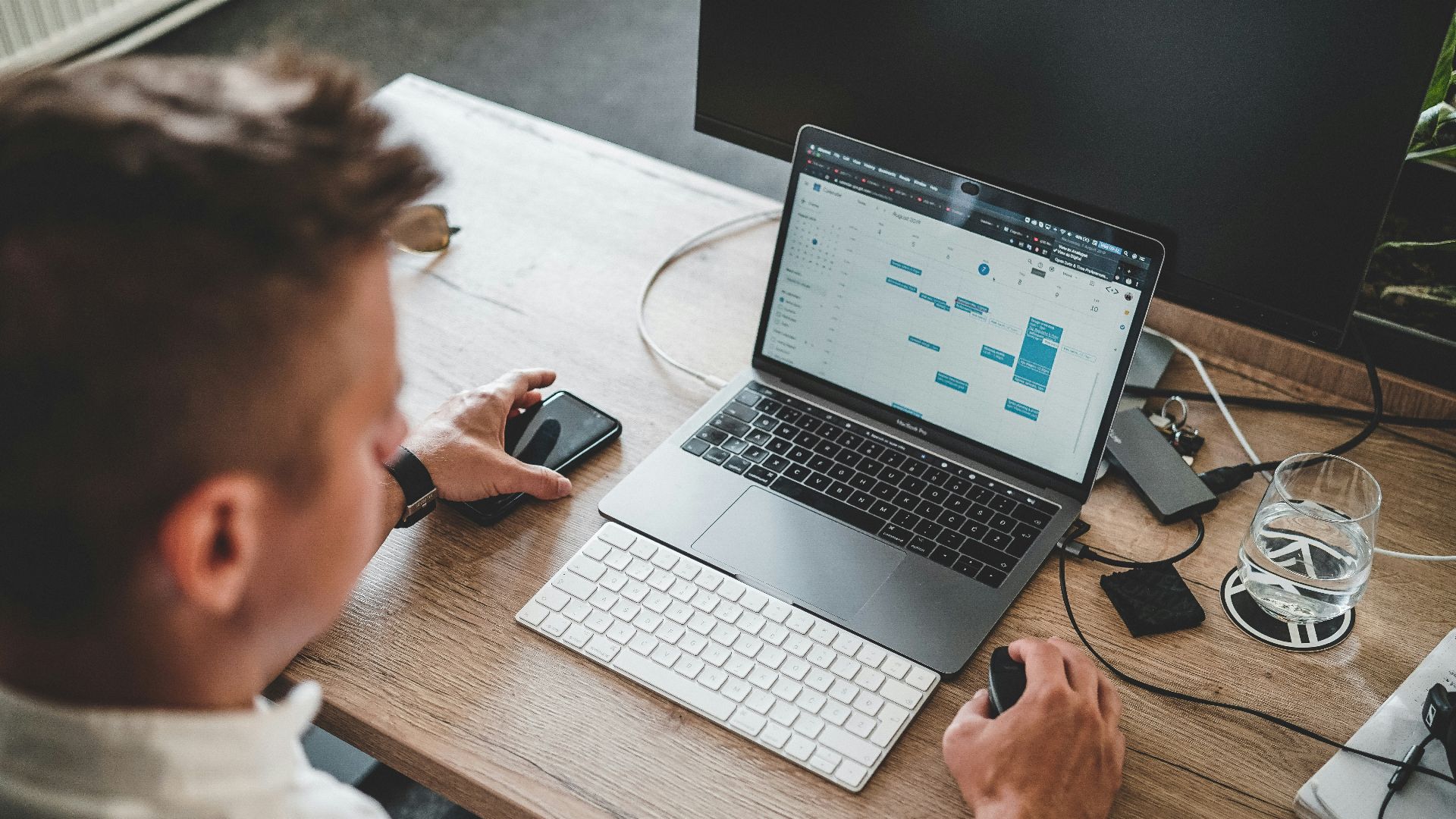 man holding mouse and iPhone while using Macbook Pro