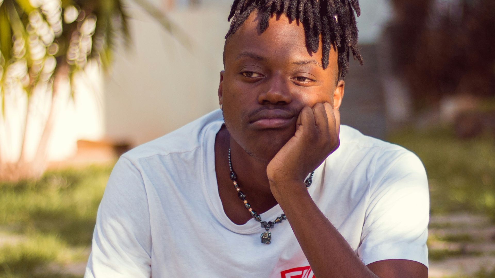man in white crew neck t-shirt sitting on brown wooden chair