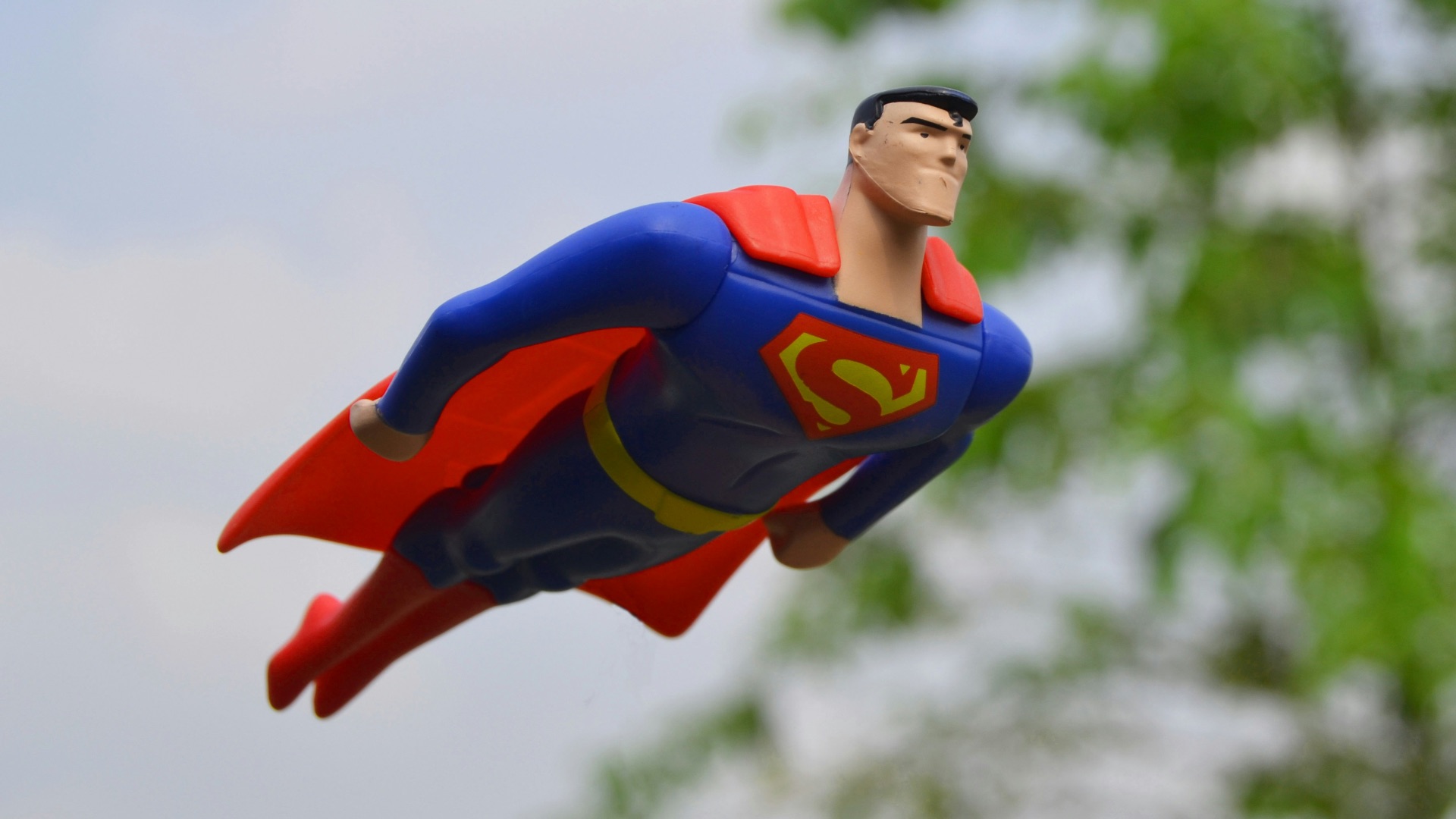 Superman flying near green grass