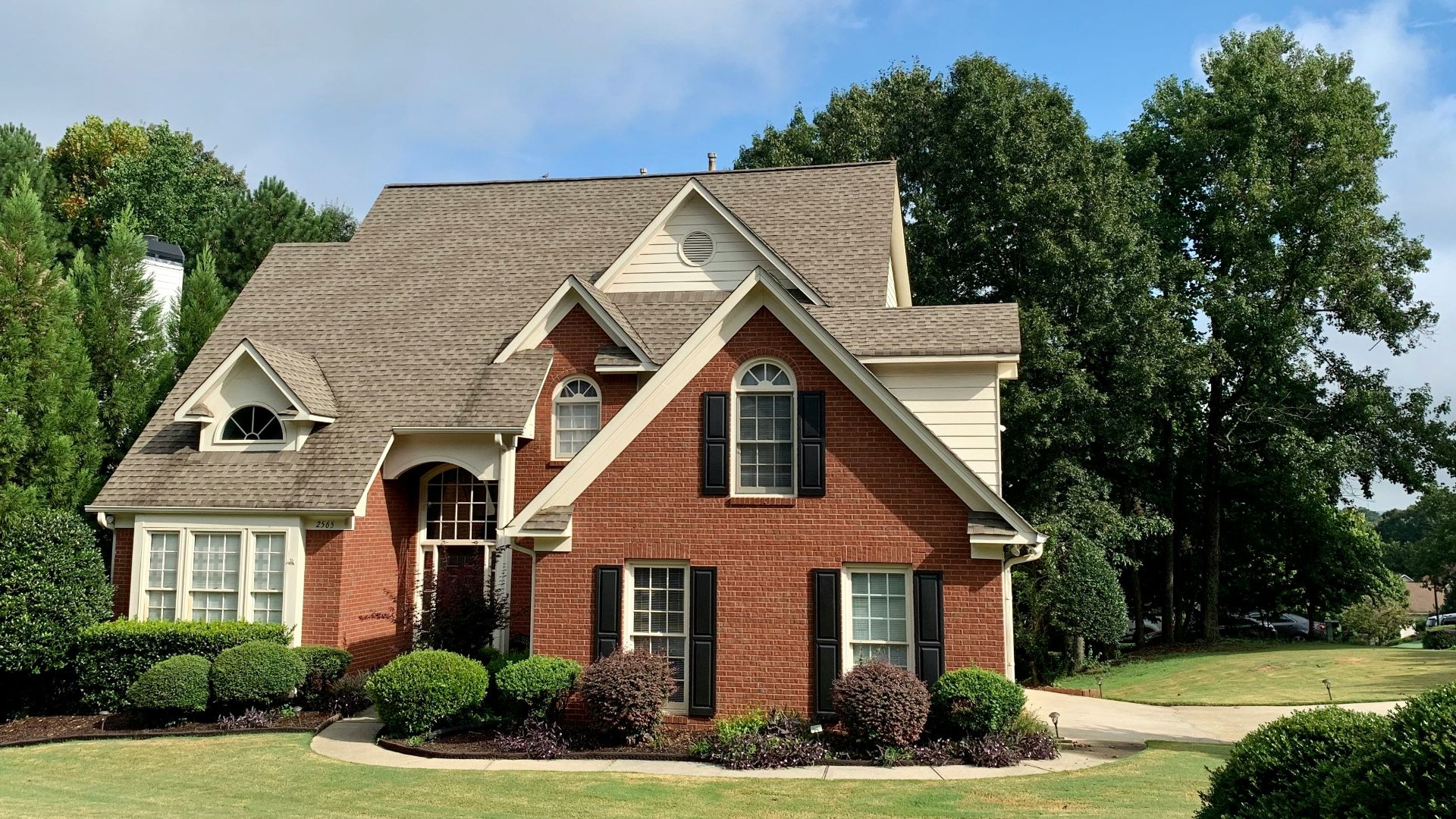 brown and white concrete house near green trees under blue sky during daytime