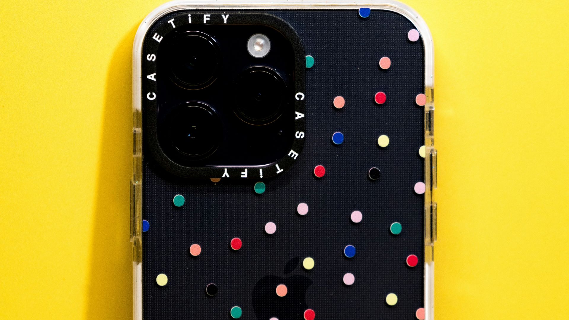 A black iPhone with a colorful polka-dot case.