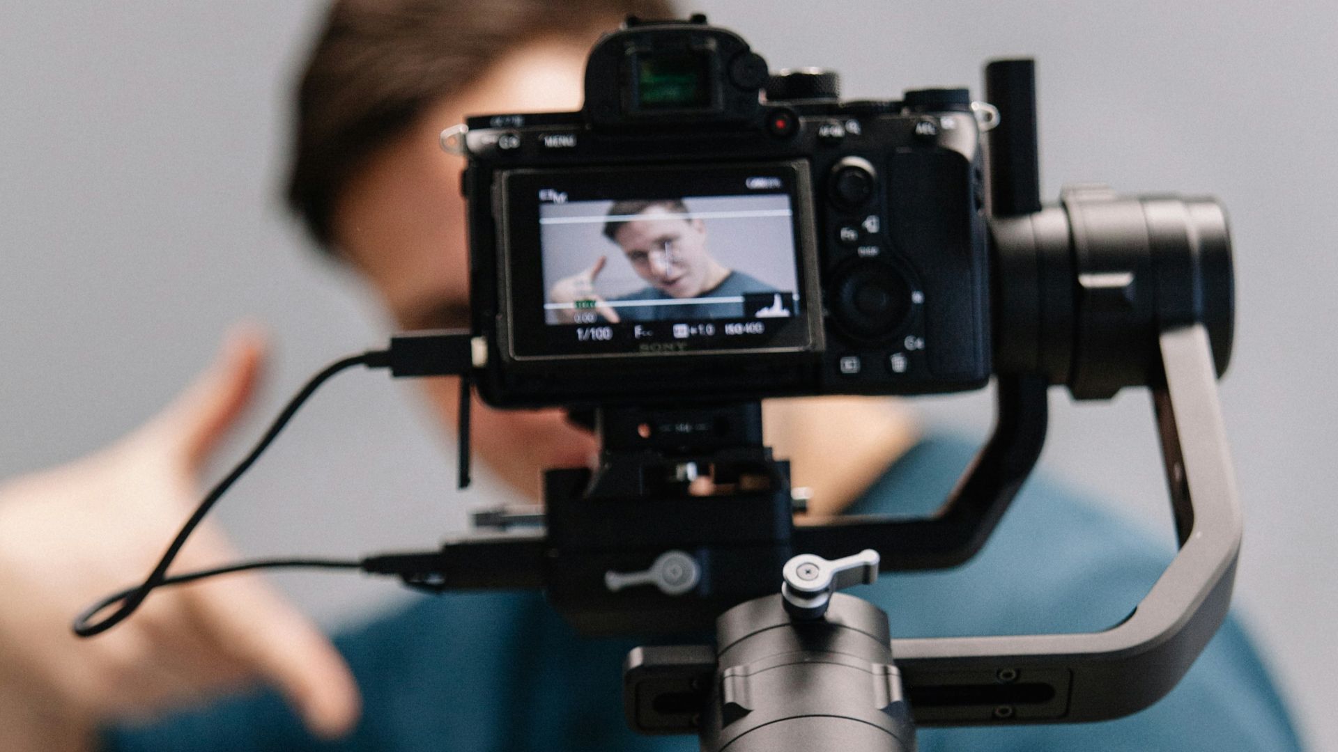 man holding black DSLR camera with stabilizer