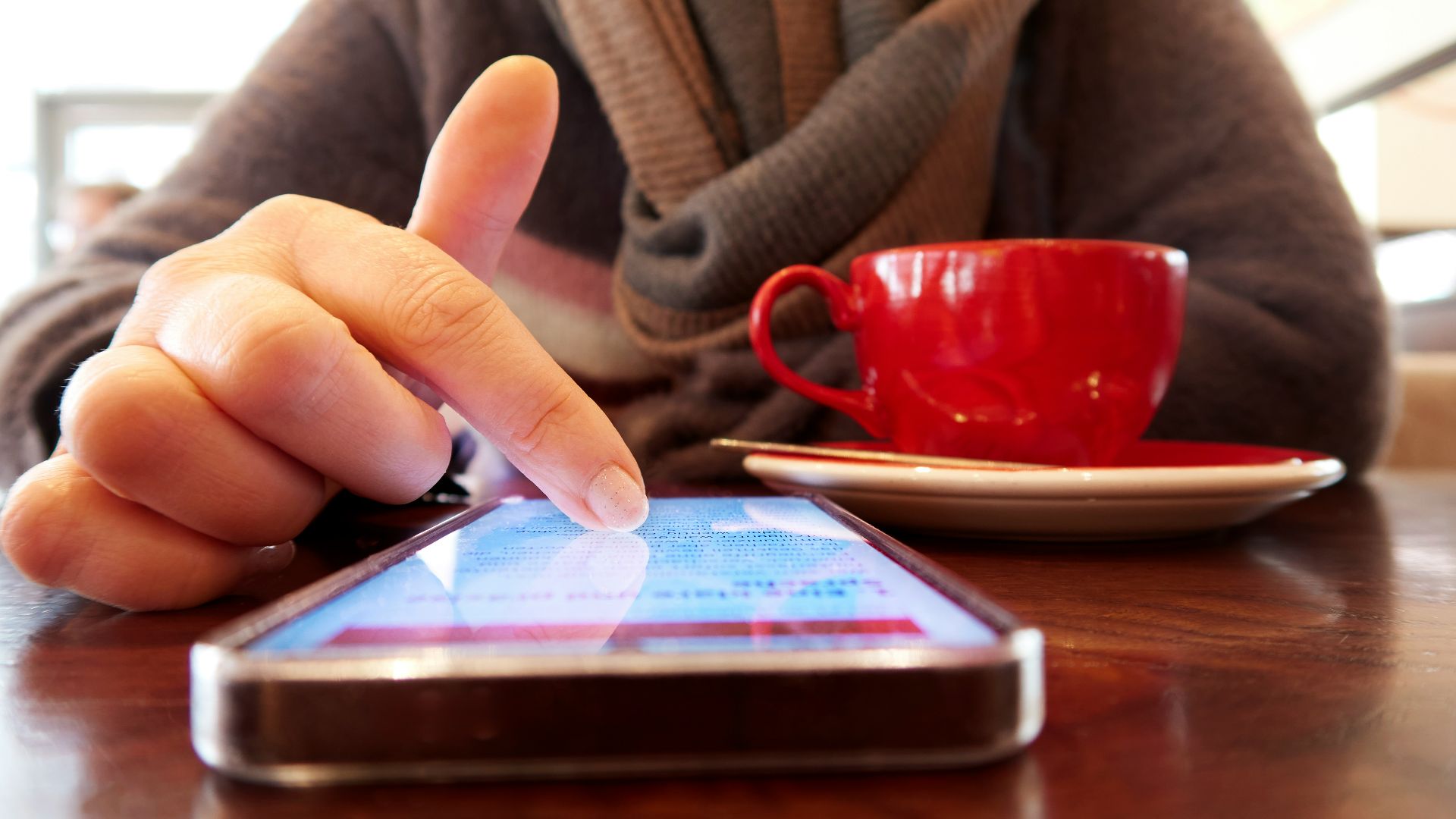 Person using a smartphone with a cup of coffee.