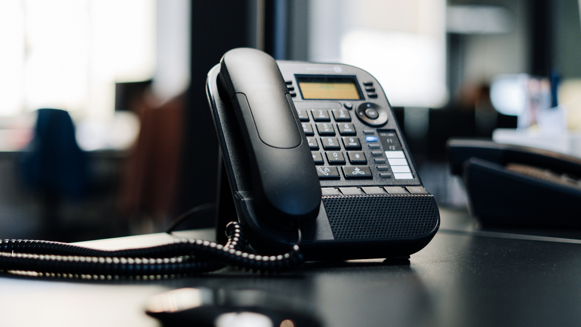 black ip desk phone on black wooden table