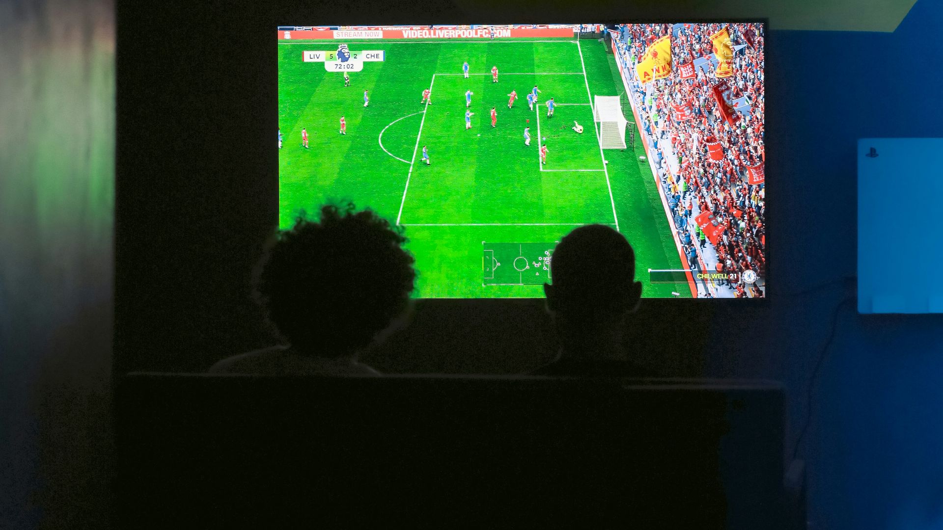Two people watching a soccer game on a television
