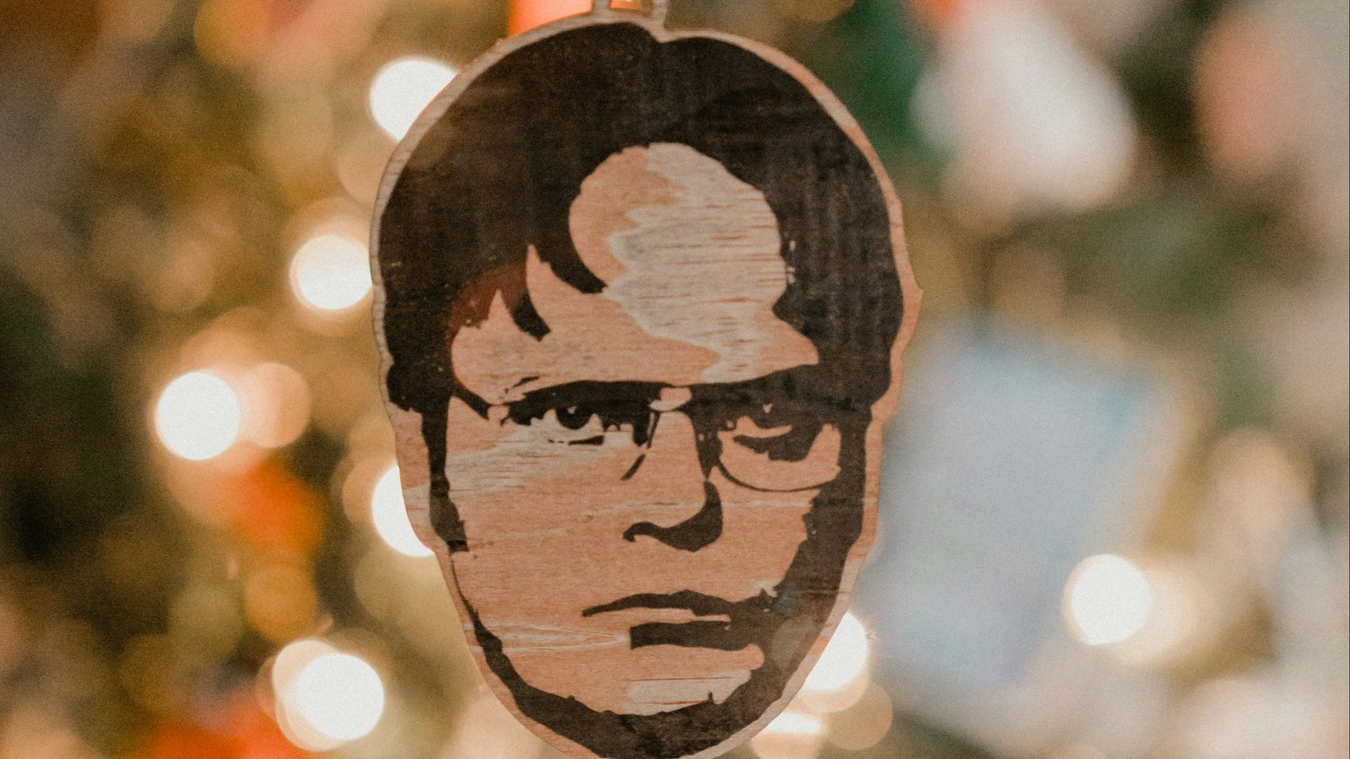 a hand holding a wooden ornament with a picture of a man on it