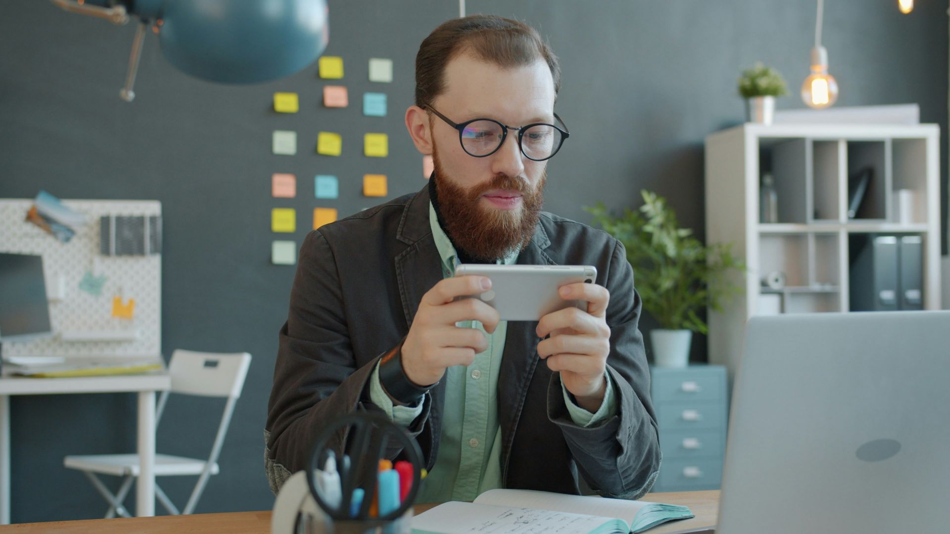 Man playing game on smartphone at office desk