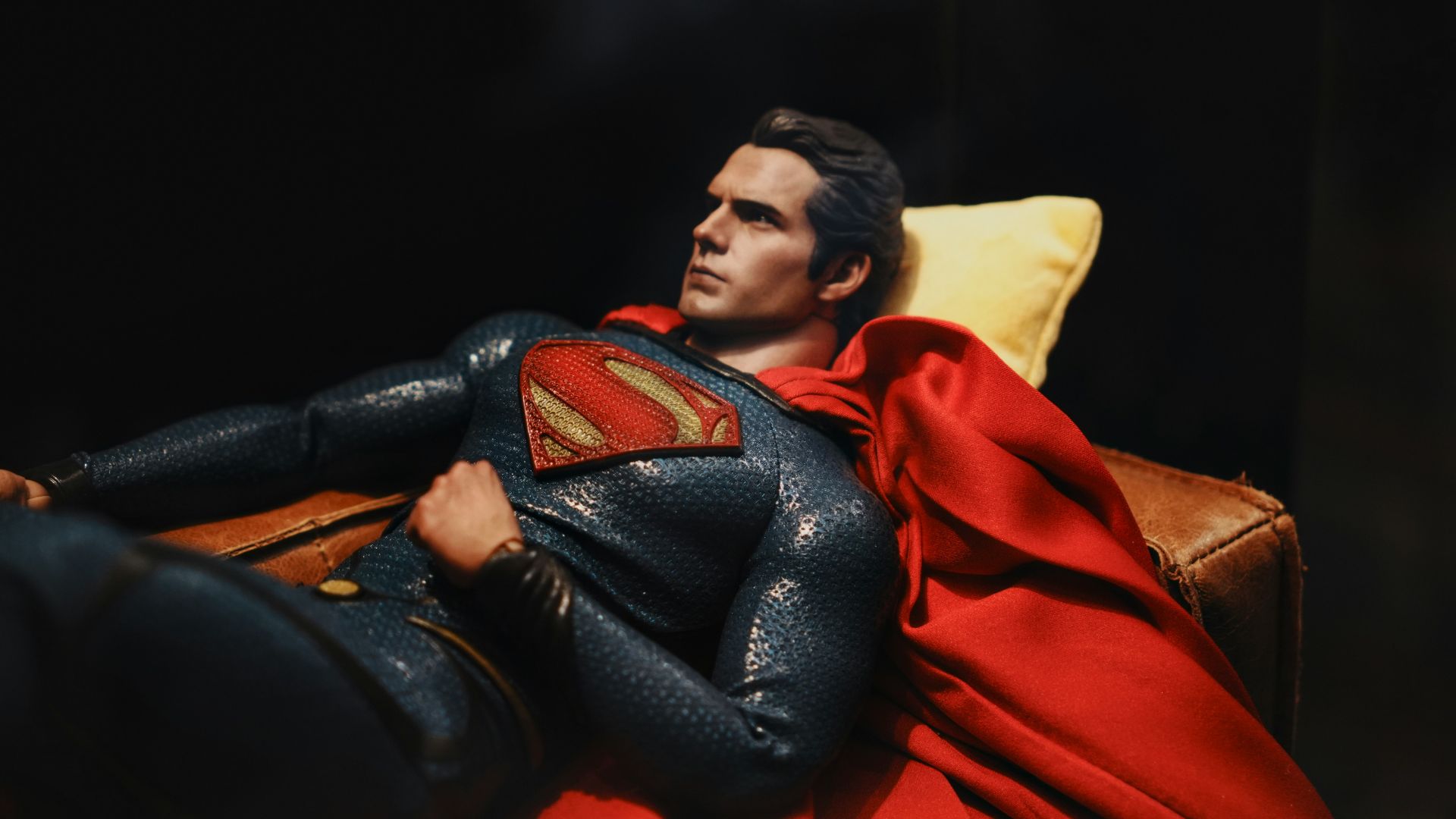 Superman relaxes on a couch, looking contemplative.