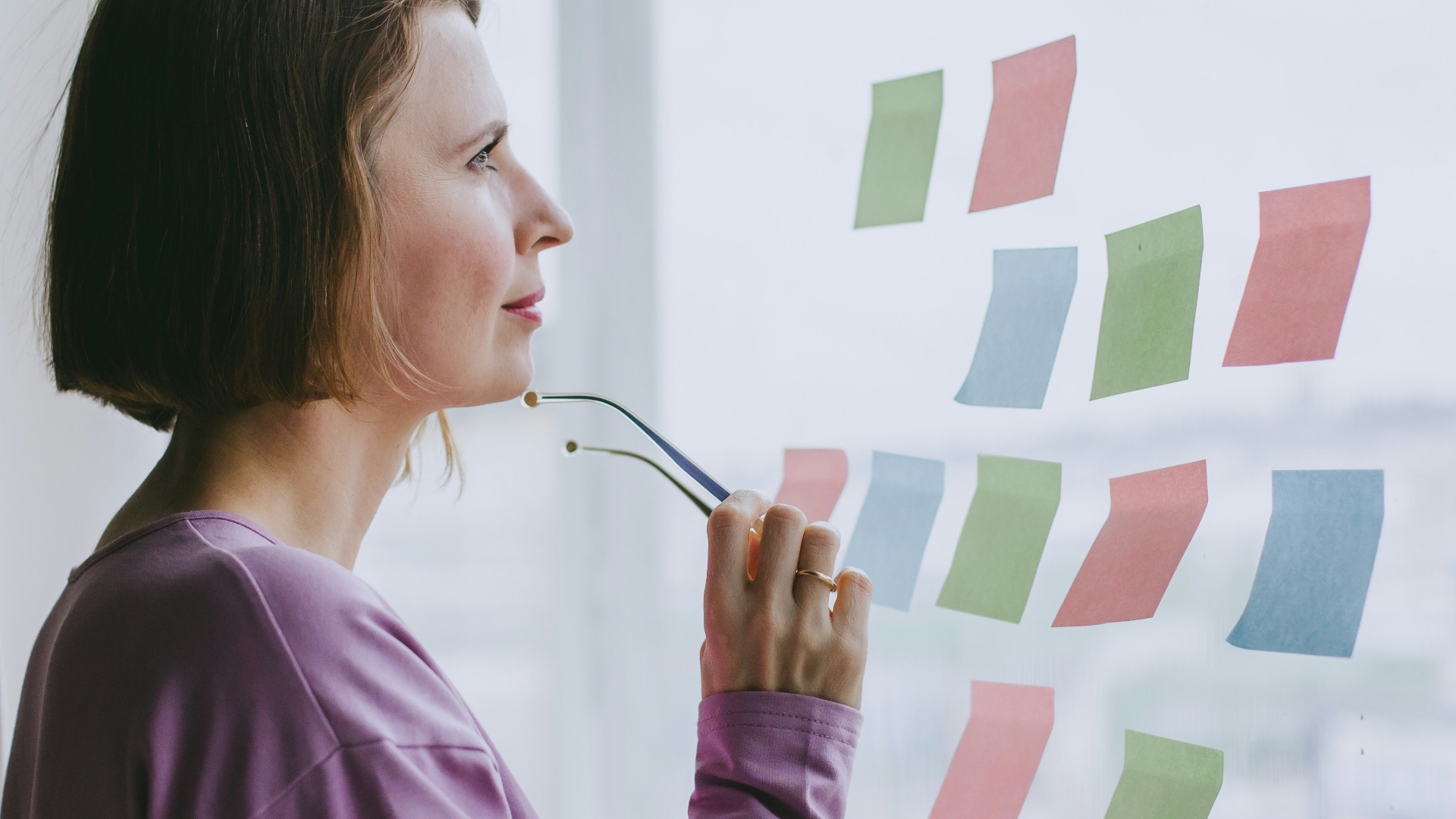 a woman looking out a window with sticky notes on it